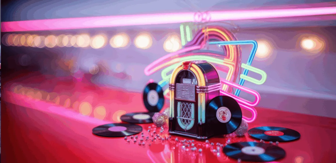 A retro jukebox surrounded by vinyl records and beads sits on a shiny red counter, with neon lights and blurred bulbs glowing in the background, creating a vibrant, nostalgic diner atmosphere.